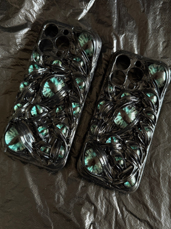 Two handmade 3D horror-themed iPhone cases featuring multiple realistic red eyes on a black textured background.
