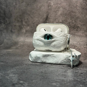 A white 3D textured AirPods case featuring a realistic glowing blue eye design with a star charm.