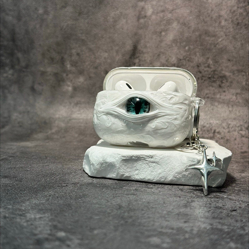 A white 3D textured AirPods case featuring a realistic glowing blue eye design with a star charm.