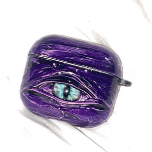 A white 3D textured AirPods case featuring a realistic glowing blue eye design with a star charm.