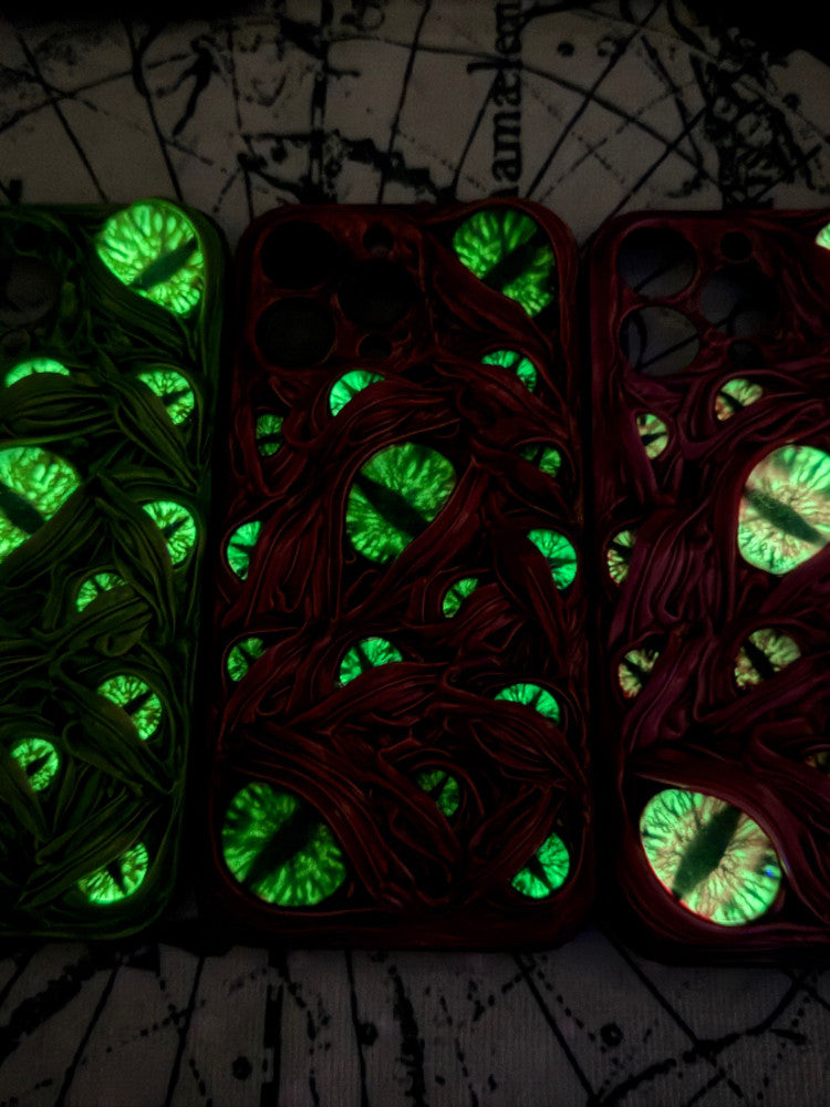 Three 3D monster eye iPhone cases in green, red, and magenta with realistic eye details.
