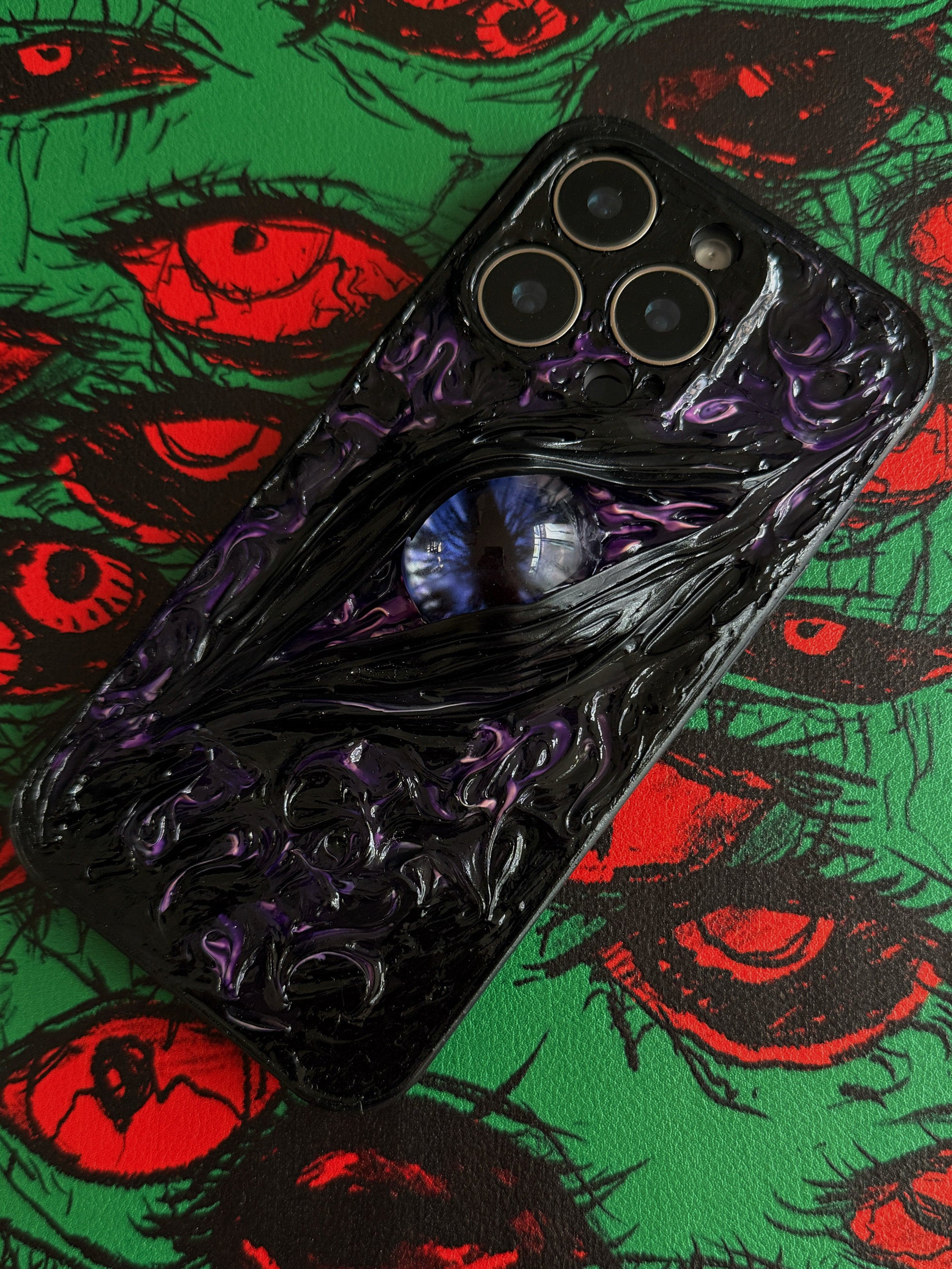 Handmade gothic iPhone case featuring a realistic 3D red eye design on a black textured background.
