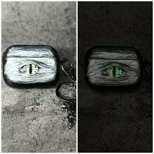 A white 3D textured AirPods case featuring a realistic glowing blue eye design with a star charm.