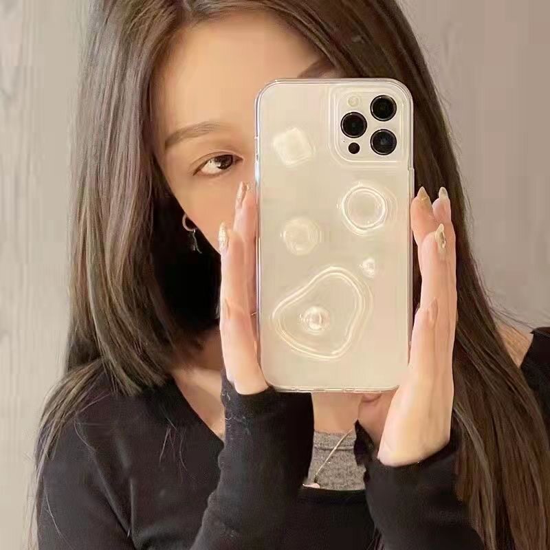 A hand holding a clear iPhone case featuring minimalist 3D pearl and abstract relief decorations.