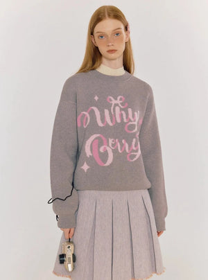 A model wearing a gray sweater with pink alphabet graphics.