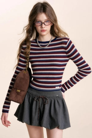 A woman wearing a red, white, and blue striped long-sleeve knit sweater.