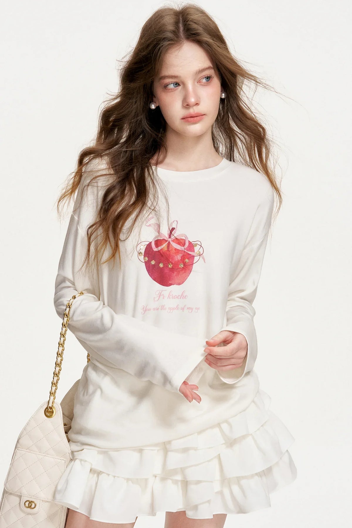 A white long-sleeve top with a hand-painted apple graphic.