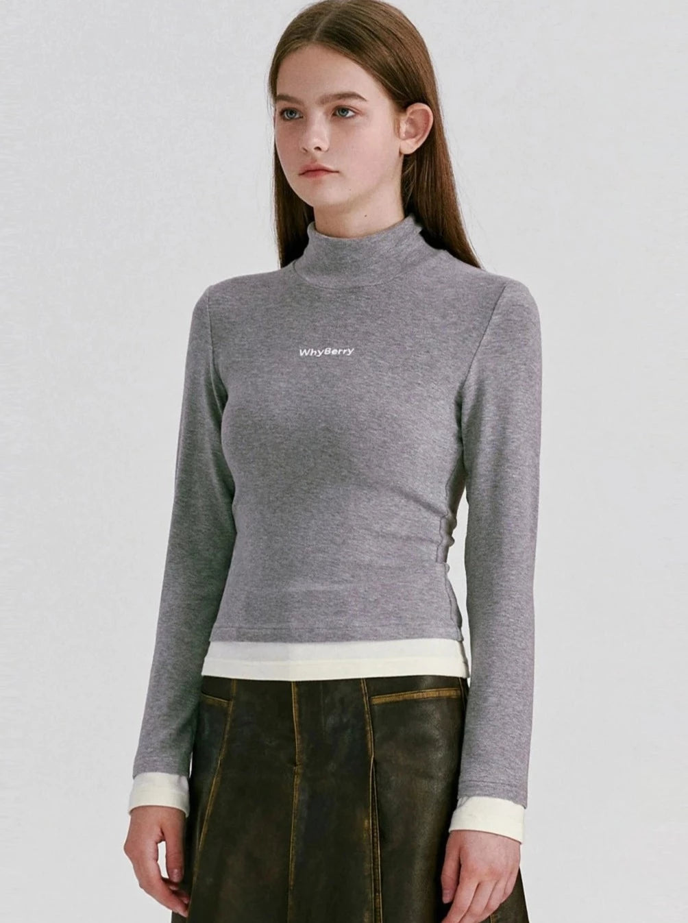 A model wearing a grey long-sleeve mock neck crop top.