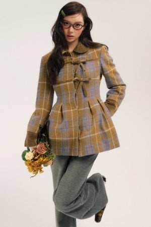 A woman wearing a turmeric plaid woolen coat with bow-tie closures.