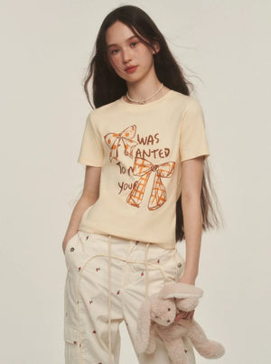 Model wearing a yellow t-shirt with a retro graffiti bow print.