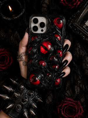 Phone case with red eyes held by a hand on a dark background with roses and spikes.