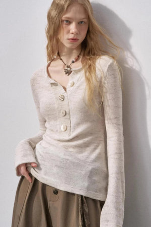A model wearing an apricot-colored knit sweater with a Henry collar and sequin details.