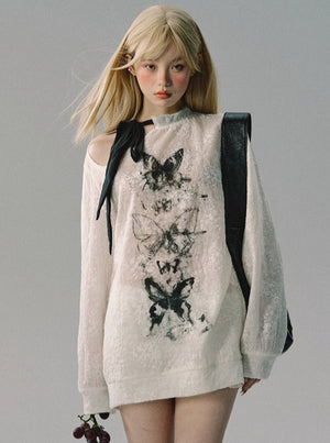 A white long-sleeve top with a butterfly graphic print and shoulder cutout.