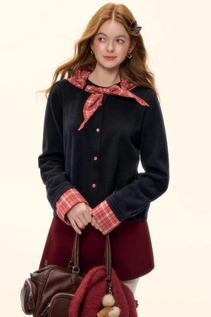 A black sweater with plaid collar and cuff details.