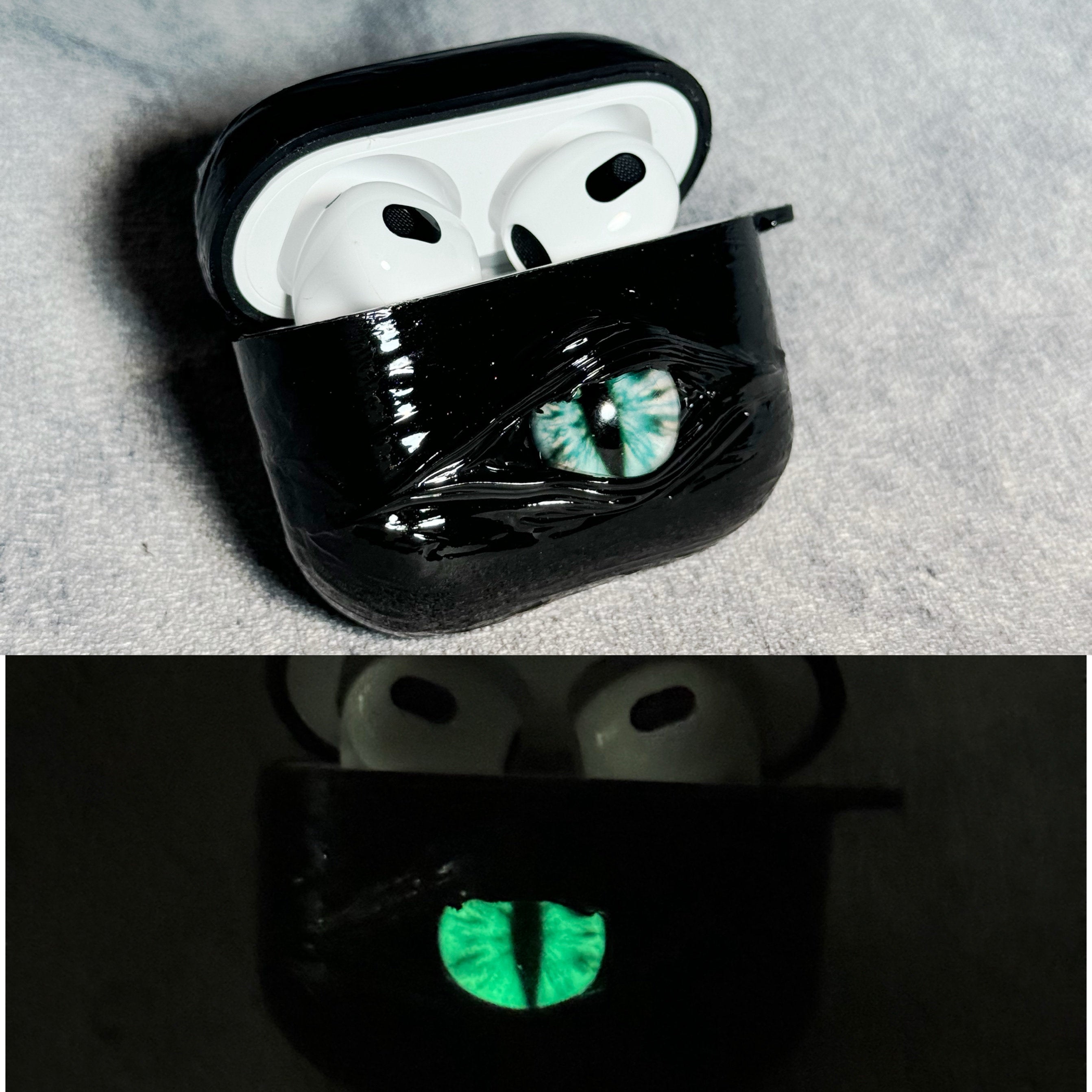 A white 3D textured AirPods case featuring a realistic glowing blue eye design with a star charm.