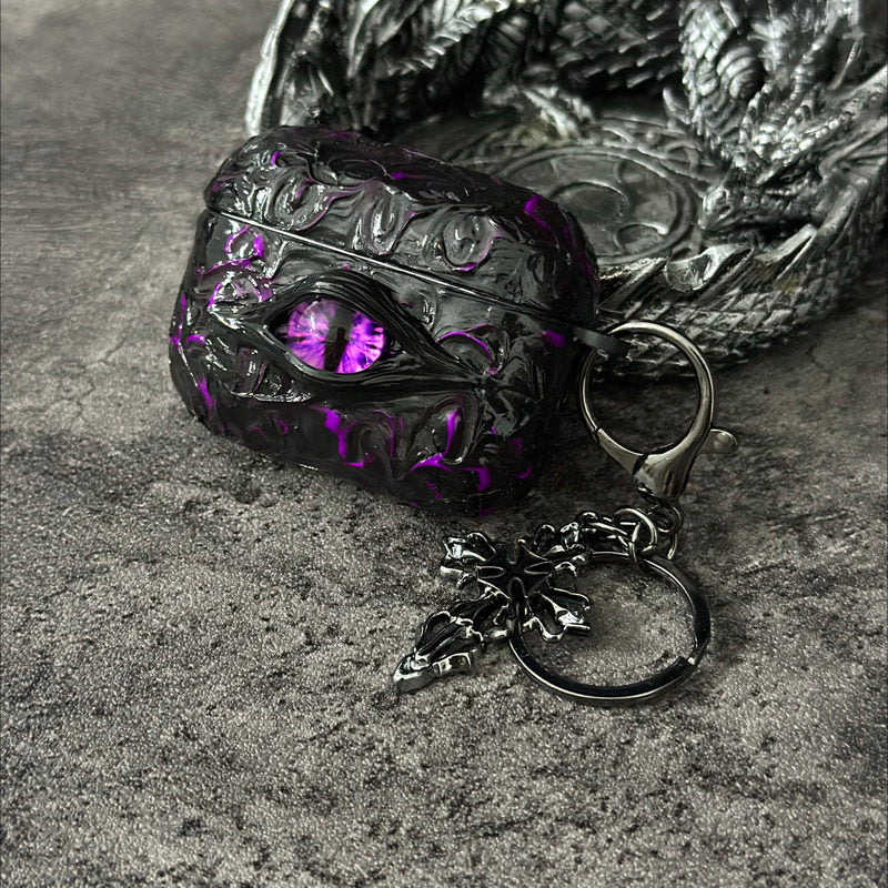 A white 3D textured AirPods case featuring a realistic glowing blue eye design with a star charm.