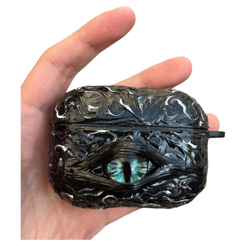 A white 3D textured AirPods case featuring a realistic glowing blue eye design with a star charm.