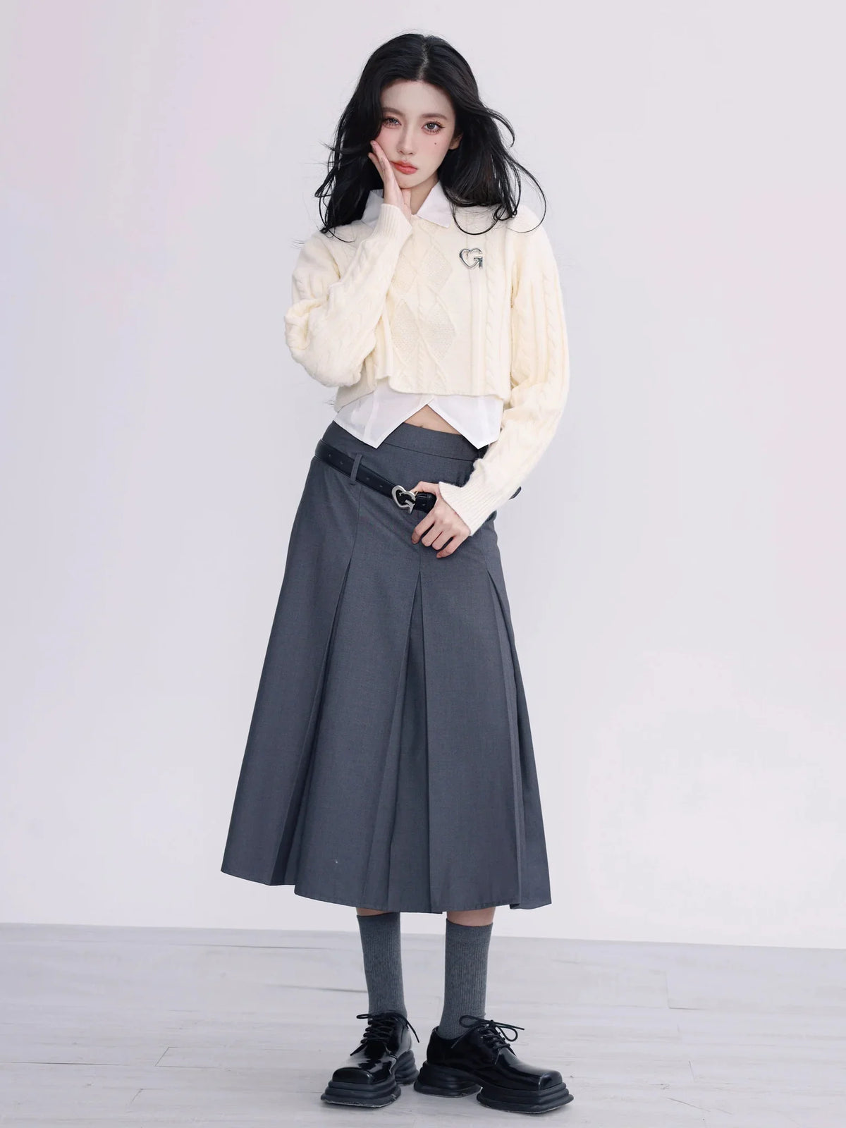 A model wearing a white cropped cable-knit sweater with a collar.