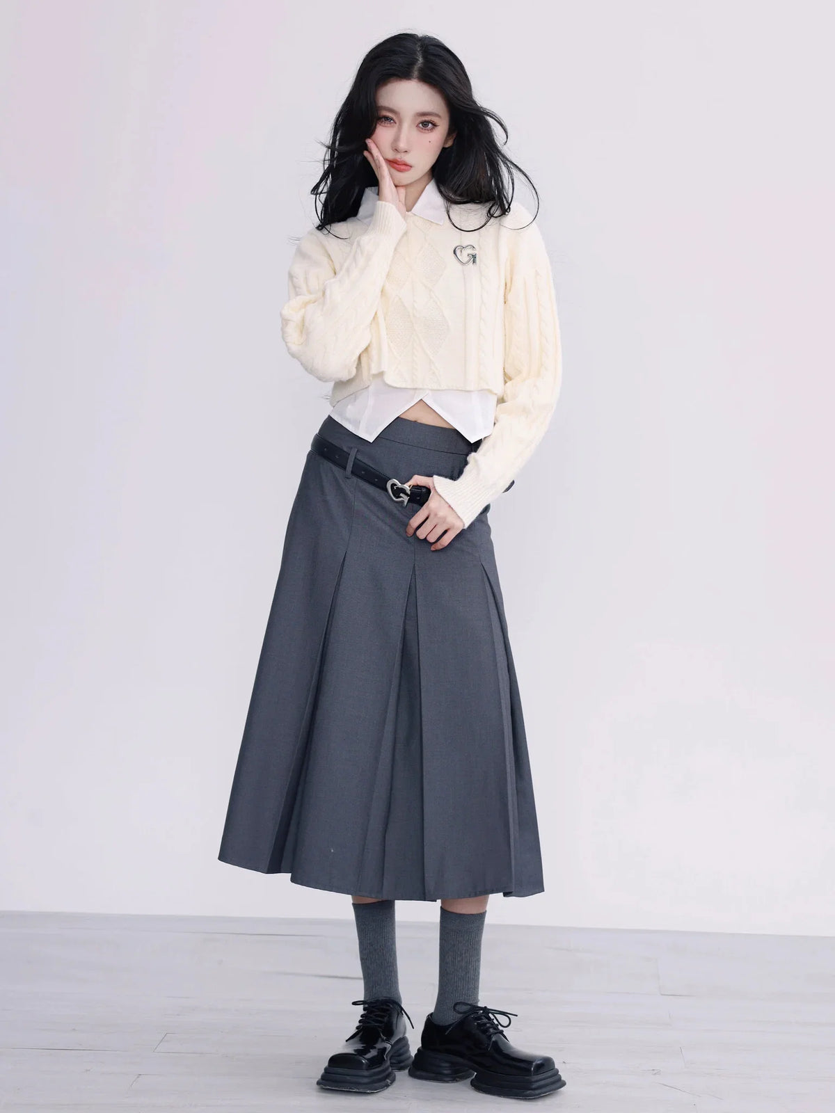 A model wearing a white cropped cable-knit sweater with a collar.