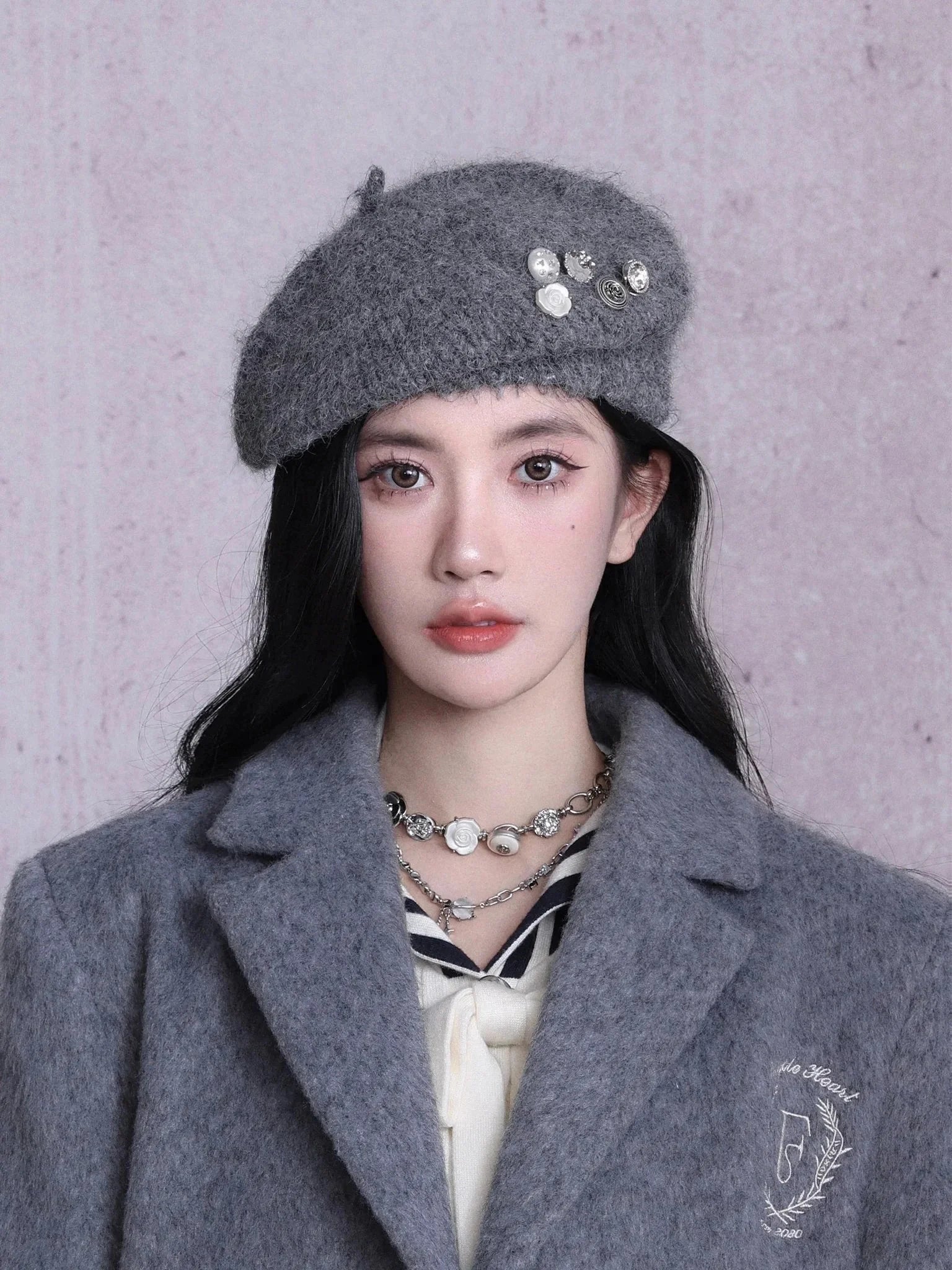 A woman wearing a black or gray beret with button embellishments.