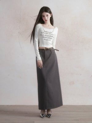 A woman wearing a long gray straight skirt with a white long-sleeve top.