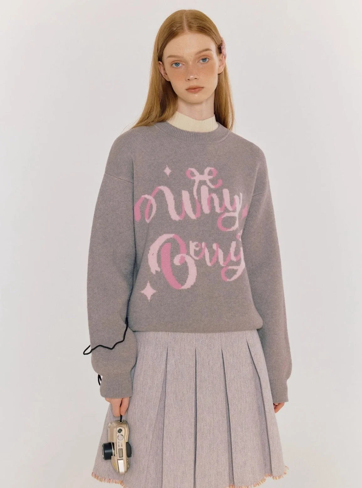A model wearing a gray sweater with pink alphabet graphics.