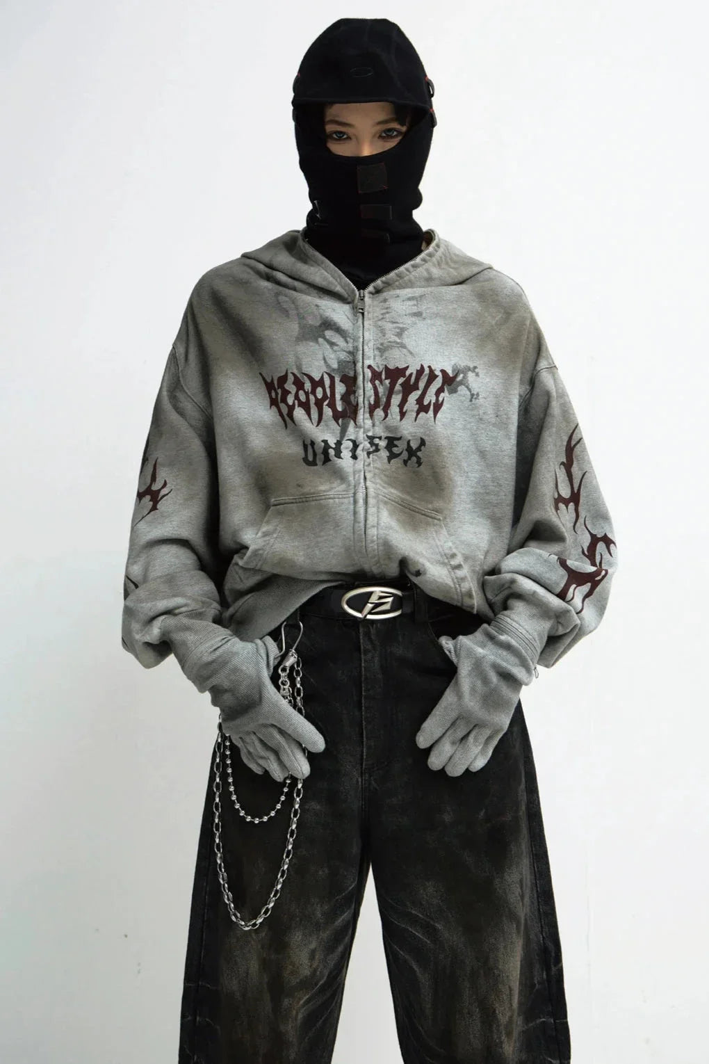 A person wearing a destruction-style loose zip-up hoodie with graphic prints.