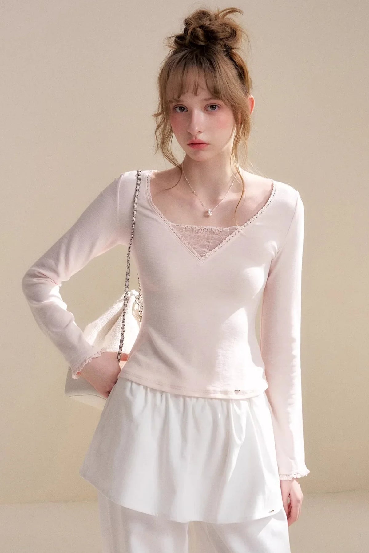 A light pink long-sleeve top with lace V-neck detailing.
