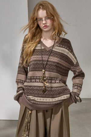 A woman wearing a brown Fair Isle patterned V-neck sweater.