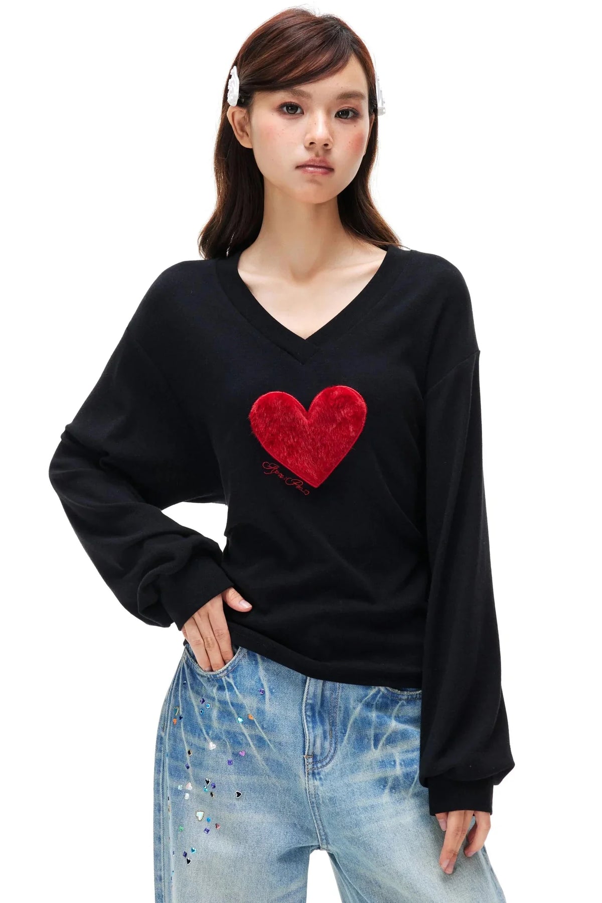 A black long-sleeve top featuring a prominent red faux fur heart on the chest.