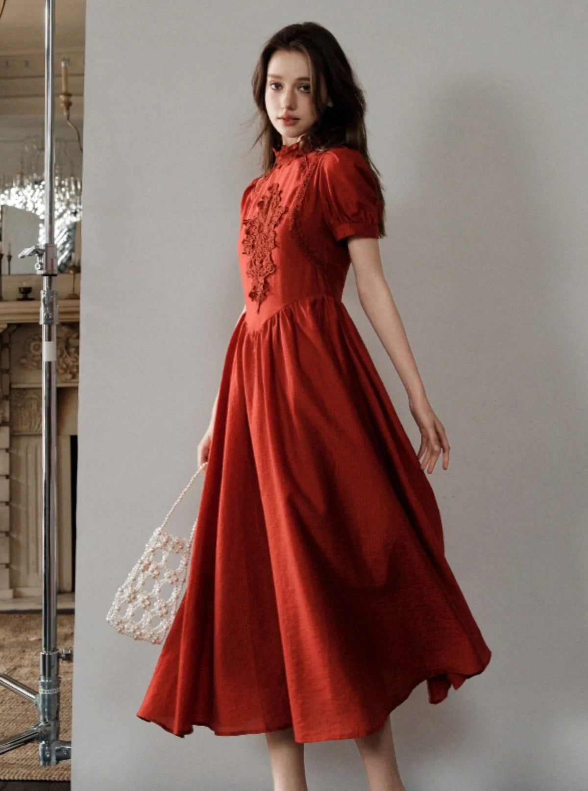 A woman wearing a red French-inspired midi dress with lace detailing.