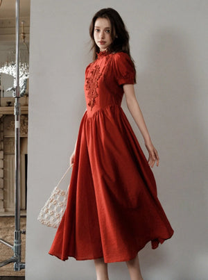 A woman wearing a red French-inspired midi dress with lace detailing.
