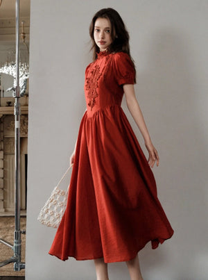 A woman wearing a red French-inspired midi dress with lace detailing.