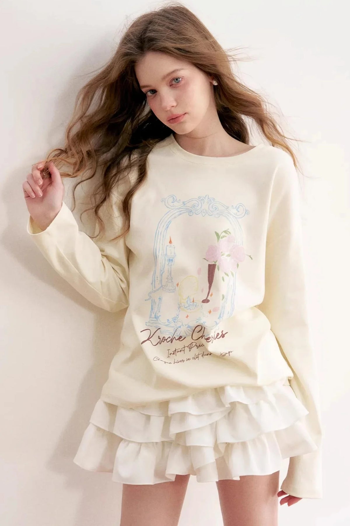 A woman wearing a vanilla custard long-sleeve top with a rose graphic.