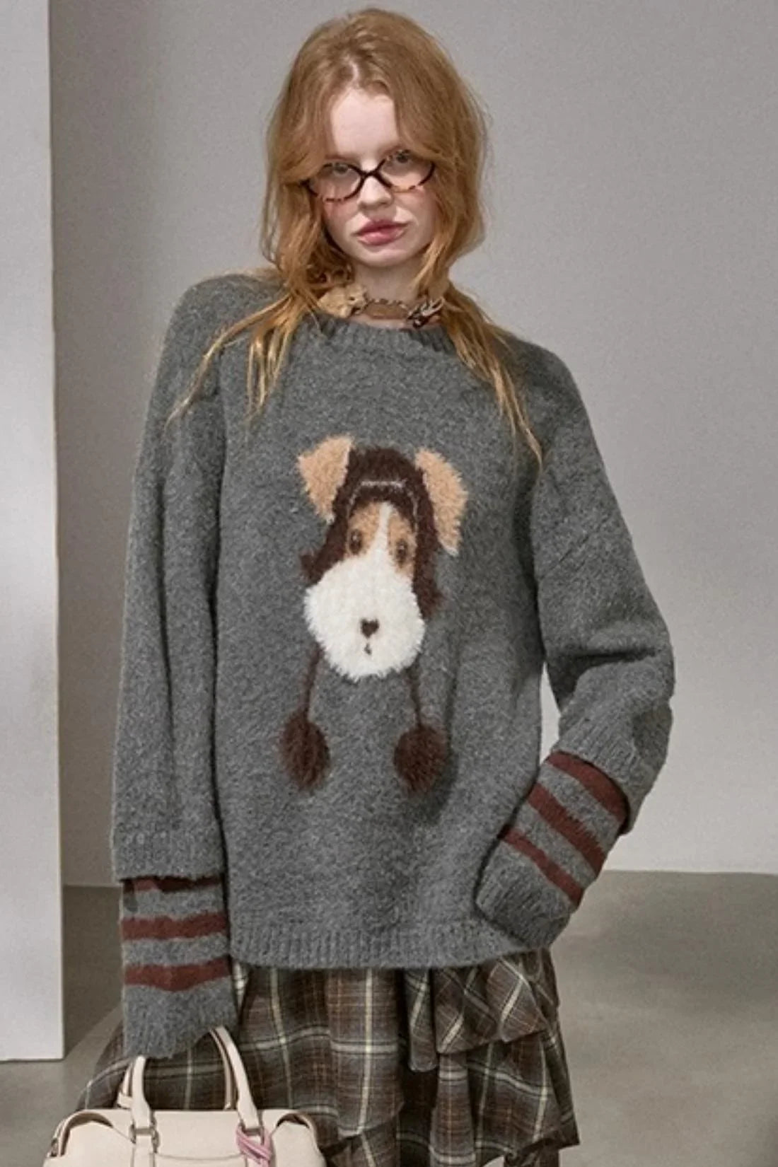 A woman wearing a gray knitted sweater with a puppy graphic.
