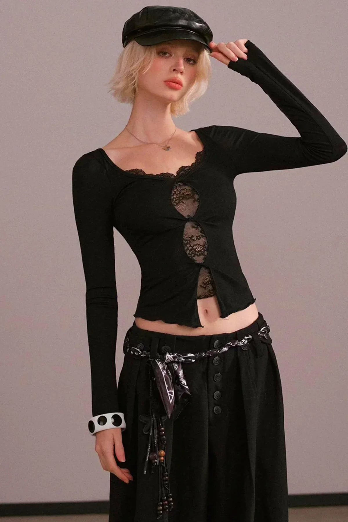 A woman wearing a black long-sleeve top with lace cutout details.