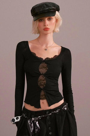 A woman wearing a black long-sleeve top with lace cutout details.