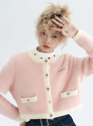 A model wearing a pink imitation mink knit jacket with white trim.