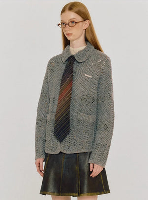 A woman wearing a gray thermal knitted cardigan jacket with a tie.