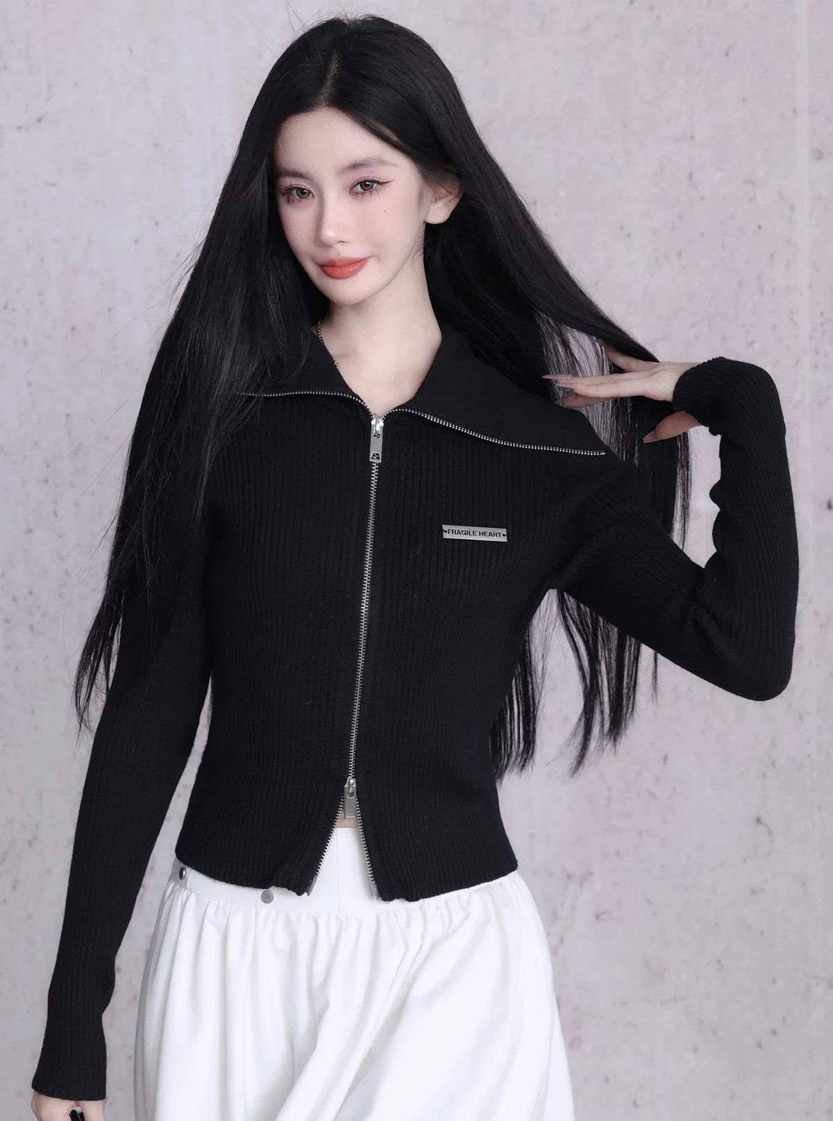 A black ribbed knit cardigan with a zipper closure and large lapels.