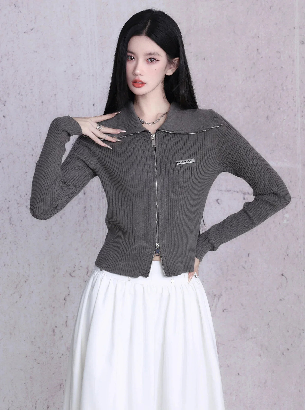 A black ribbed knit cardigan with a zipper closure and large lapels.