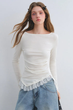 A white long-sleeve top with lace patchwork at the hem.