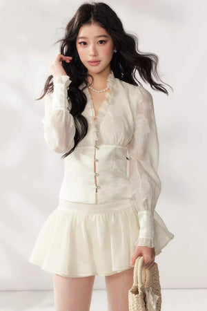 A white two-piece lace skirt set featuring a V-neck top and matching skirt.