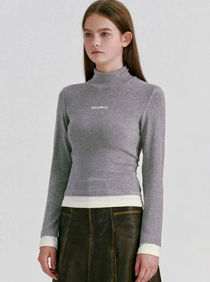 A model wearing a grey long-sleeve mock neck crop top.