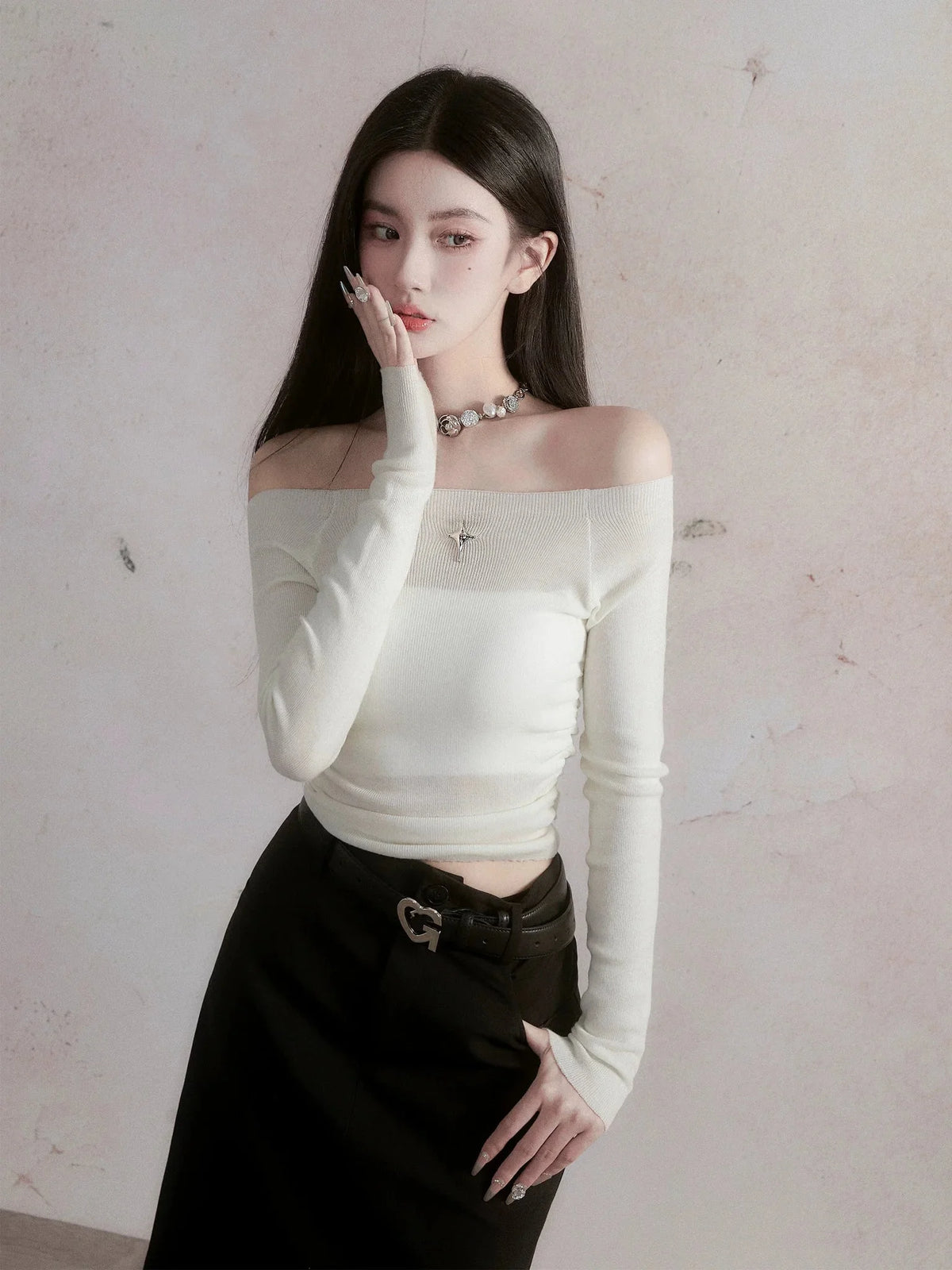 A woman wearing a long-sleeved white top with an off-shoulder neckline.