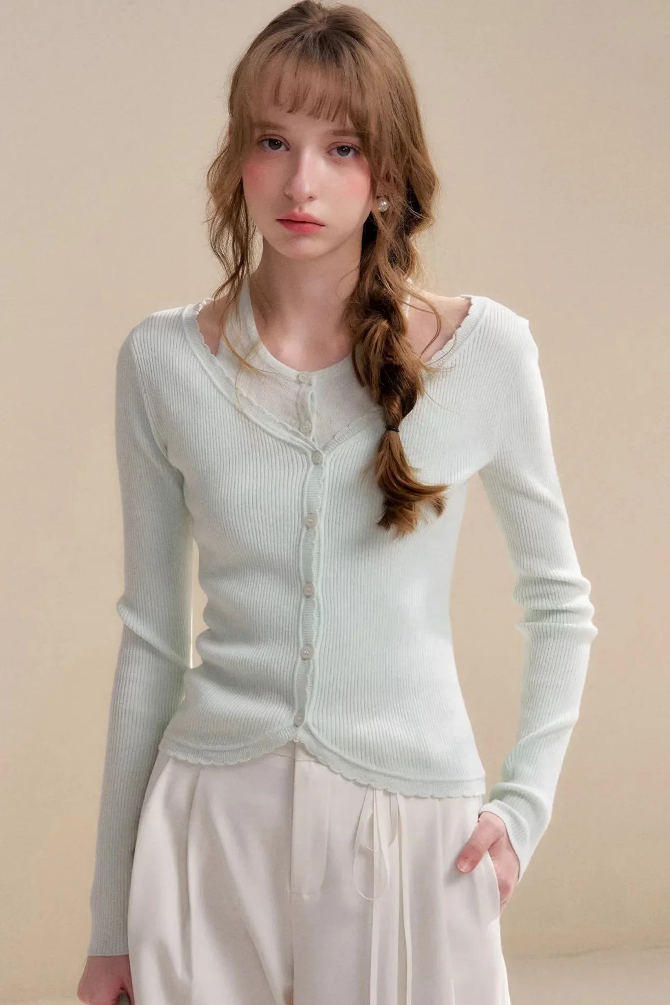 A model wearing a soft mint green wool cardigan with a button-down front.