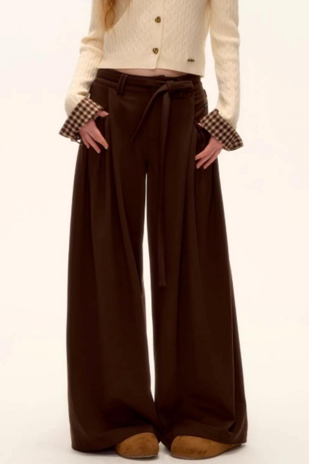 A woman wearing brown pleated wide-leg pants.
