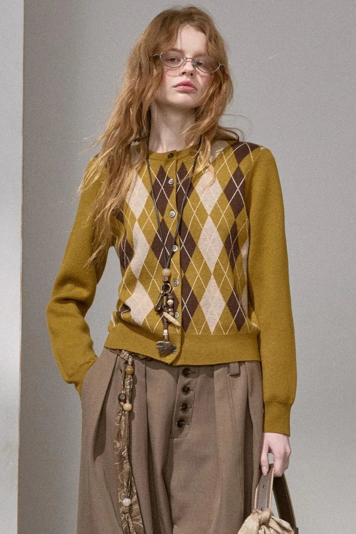 A woman wearing an autumn pear colored diamond-pattern knit top.
