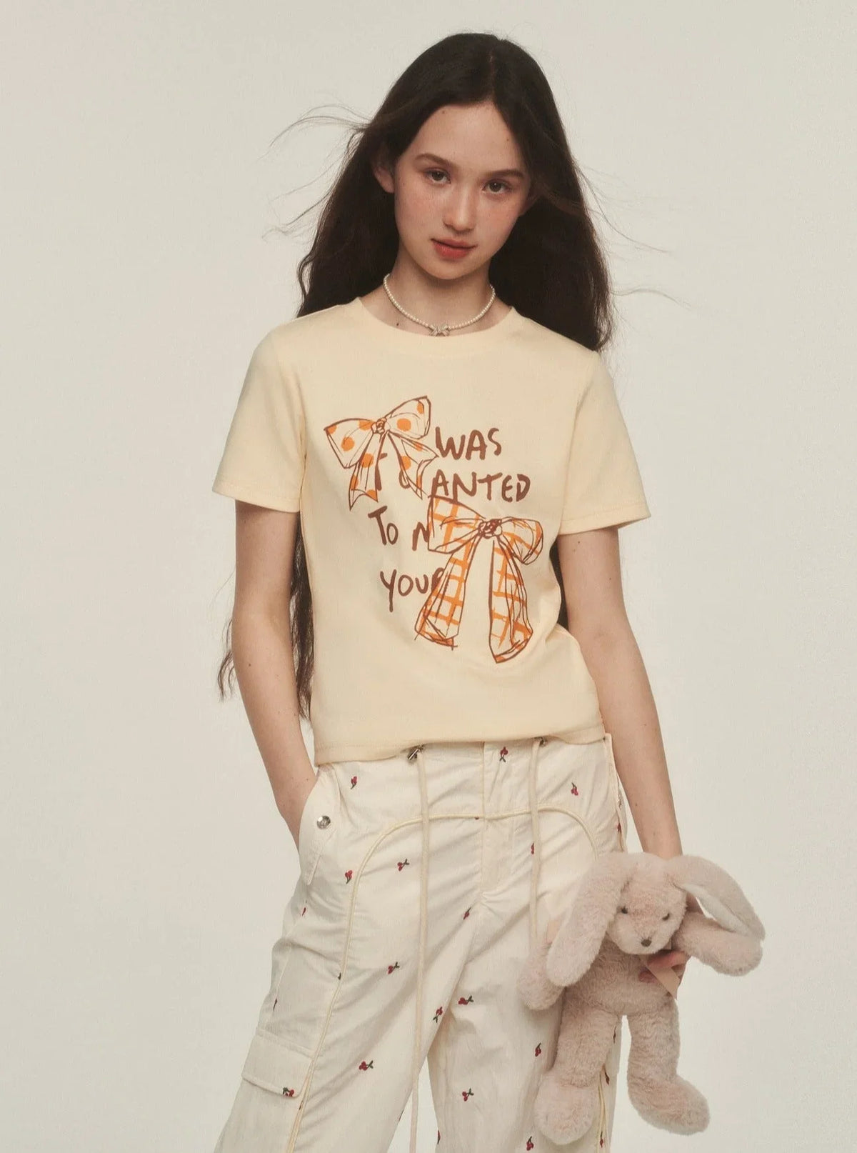 Model wearing a yellow t-shirt with a retro graffiti bow print.
