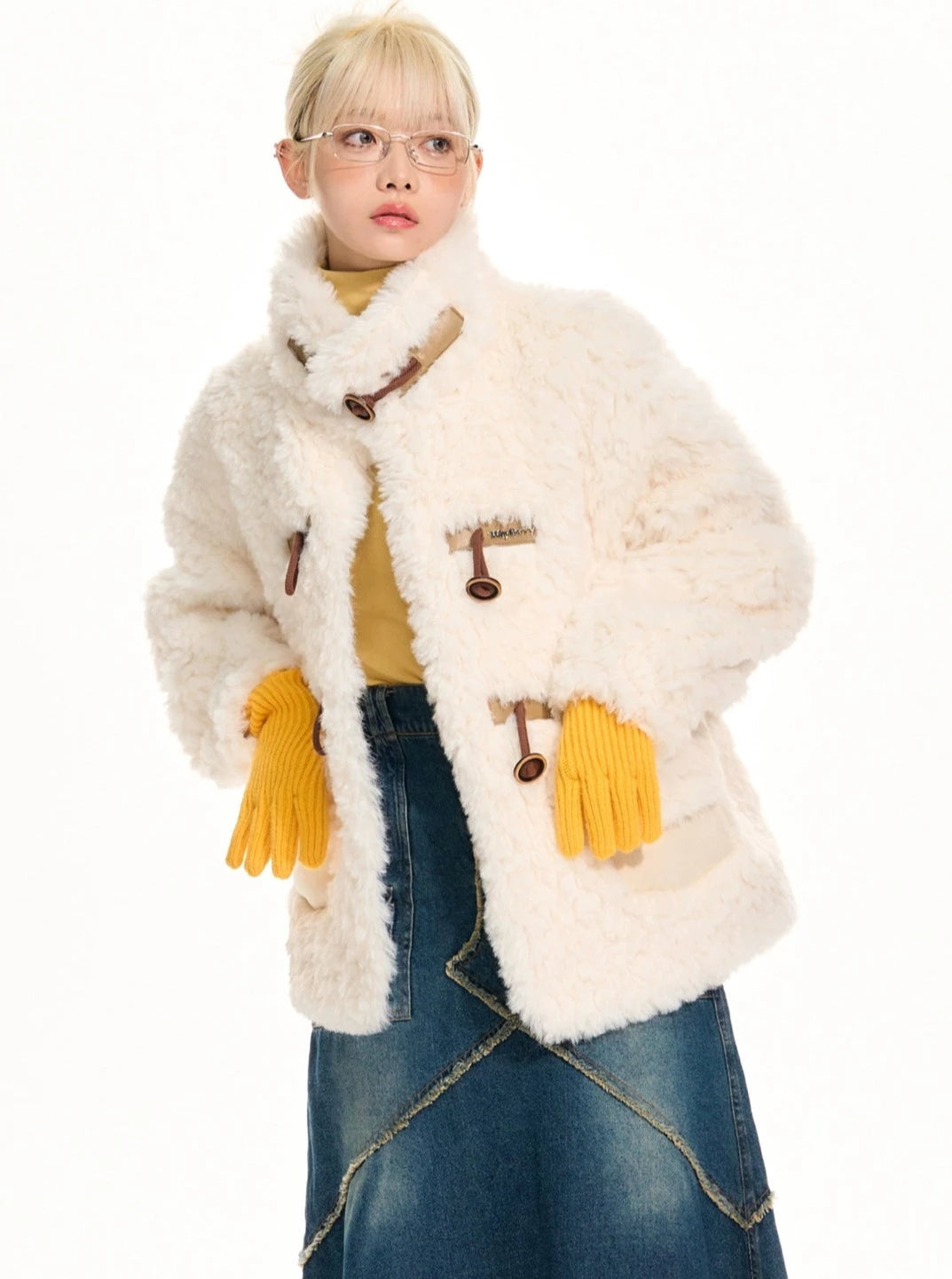 A person wearing a white fleece jacket with horn buckle closures.